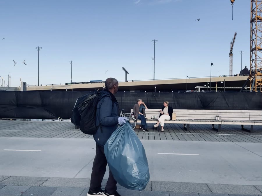 First frame of a Live Photo burst showing a person walking with a blue bag.